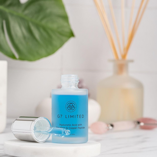 A sleek glass bottle of G7 Hyaluronic Acid Serum with a dropper cap, containing a lightweight, hydrating formula infused with squalane and copper peptides, set against a clean, minimalist background